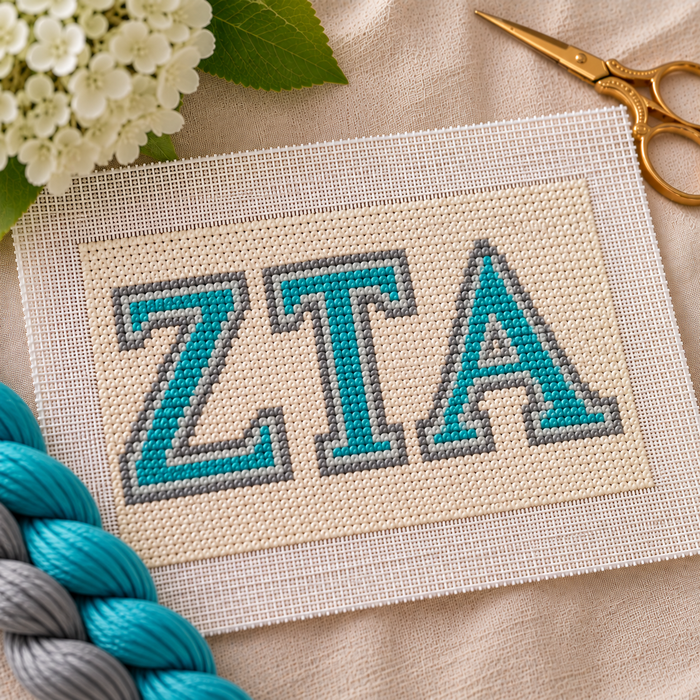 Zeta Tau Alpha needlepoint canvas with ΖΤΑ letters and gold crown motif over turquoise blue and steel gray stripes